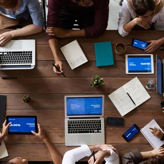 A tabletop view of laptops, notes, and phones during a policy meeting